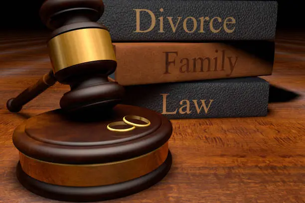 Gavel and wedding rings beside divorce and family law books